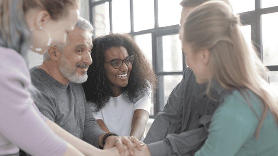 Group of people smiling with hands together working with integrity